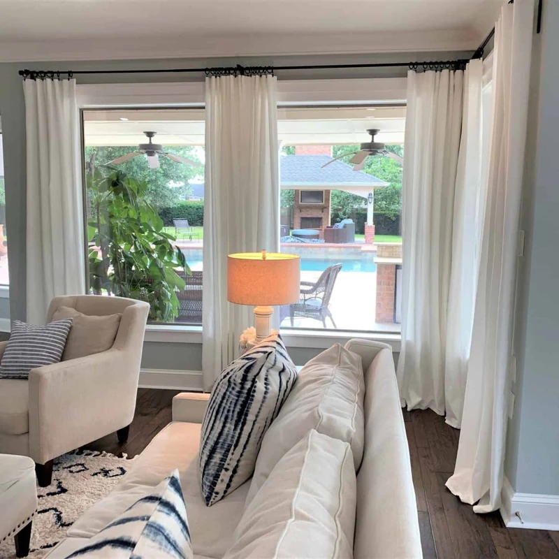 White curtain with black rod framing pool view