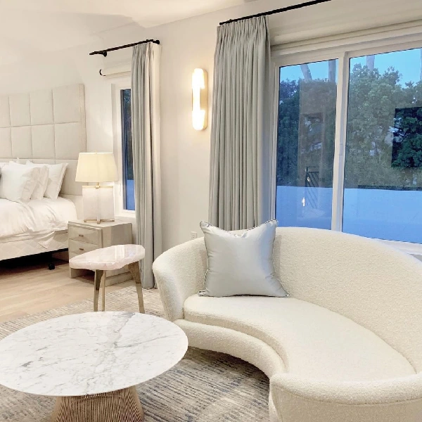 custom curved white boucle sofa with a silver pillow in a luxurious bedroom